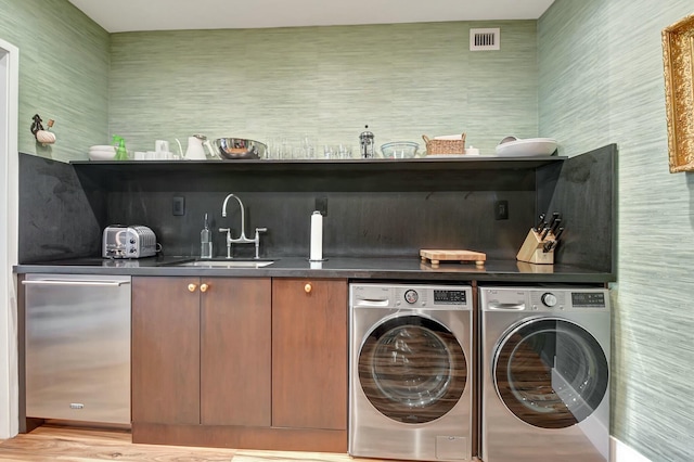 clothes washing area with separate washer and dryer, light hardwood / wood-style floors, and sink