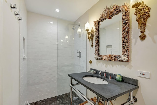 bathroom with tiled shower and sink