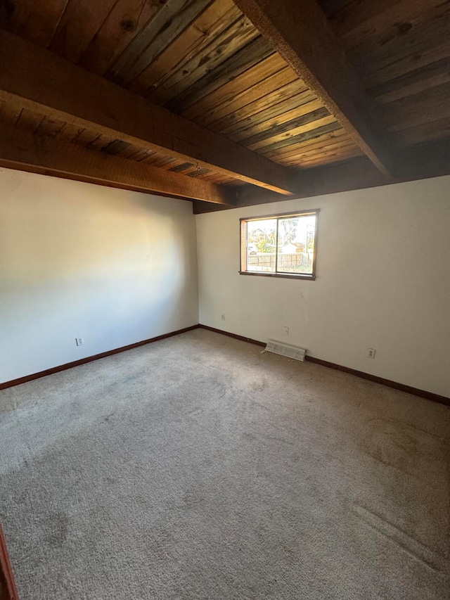 spare room featuring beamed ceiling, wood ceiling, and carpet flooring