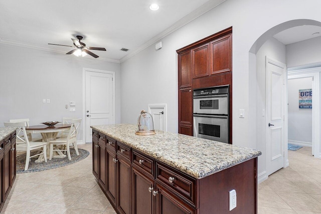 kitchen featuring crown molding, a kitchen island, stainless steel double oven, and light tile patterned floors