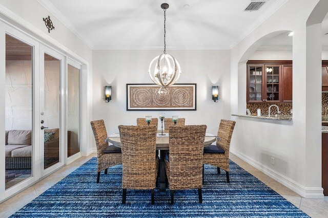 dining area featuring ornamental molding, light tile patterned floors, and an inviting chandelier