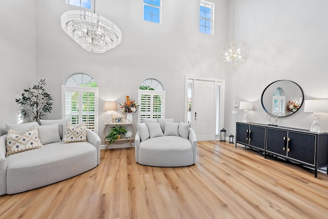 living room featuring a towering ceiling, a chandelier, and light hardwood / wood-style floors