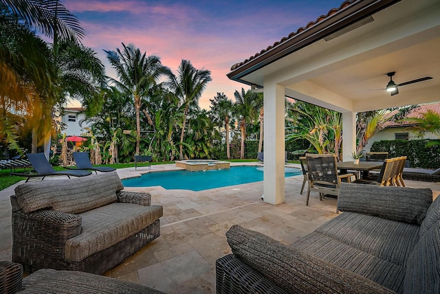 pool at dusk featuring an in ground hot tub, outdoor lounge area, ceiling fan, and a patio area