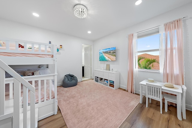 bedroom featuring baseboards, recessed lighting, wood finished floors, and a notable chandelier