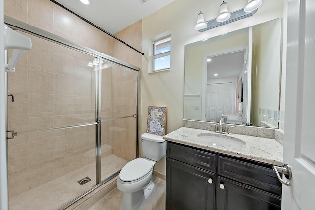 bathroom featuring tile patterned flooring, toilet, a shower with door, and vanity