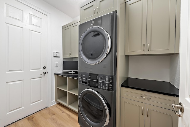 laundry area with light wood-type flooring, stacked washer and clothes dryer, and cabinet space