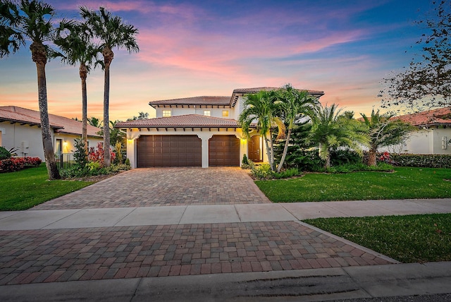 mediterranean / spanish-style house featuring a garage, a front lawn, decorative driveway, and a tiled roof