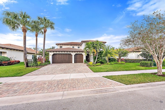 mediterranean / spanish home with a garage, a tile roof, a front lawn, and decorative driveway