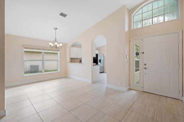 tiled entryway featuring a chandelier and vaulted ceiling