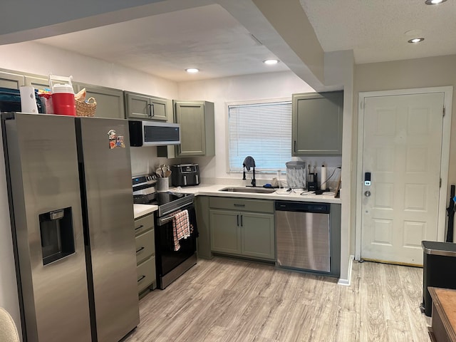 kitchen featuring a textured ceiling, sink, light hardwood / wood-style flooring, and appliances with stainless steel finishes