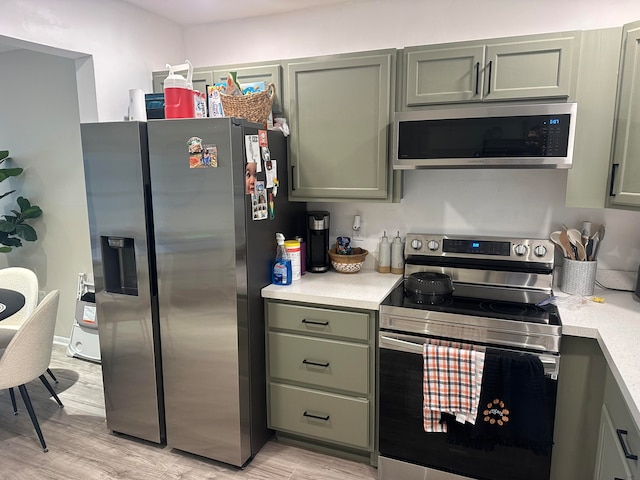 kitchen featuring green cabinets, light wood-type flooring, and appliances with stainless steel finishes