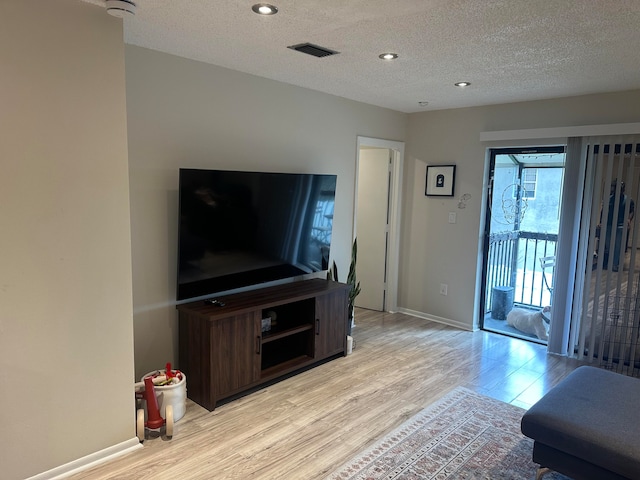 living room with light wood-type flooring and a textured ceiling