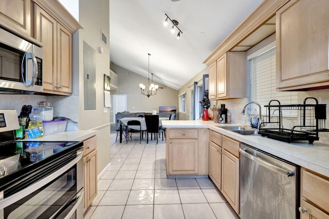 kitchen featuring vaulted ceiling, a notable chandelier, sink, appliances with stainless steel finishes, and light brown cabinetry