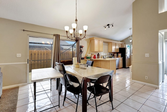 tiled dining room with sink, a chandelier, vaulted ceiling, and track lighting