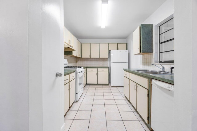 kitchen with light tile patterned floors, sink, decorative backsplash, white appliances, and cream cabinetry