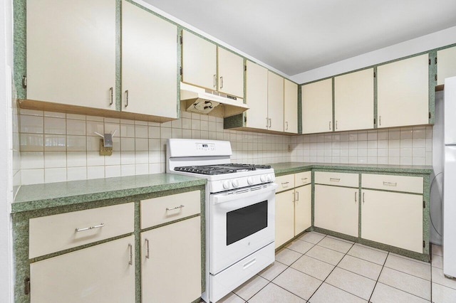 kitchen with decorative backsplash, cream cabinets, light tile patterned flooring, and white appliances