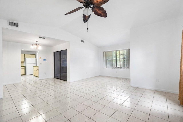 empty room featuring ceiling fan with notable chandelier, light tile patterned floors, and vaulted ceiling