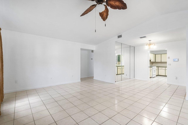 tiled spare room featuring ceiling fan with notable chandelier and lofted ceiling