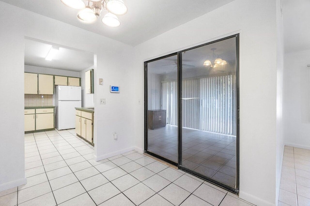 kitchen featuring light tile patterned floors, white fridge, cream cabinets, and decorative backsplash