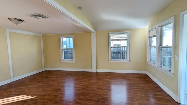 empty room featuring dark wood-type flooring and a healthy amount of sunlight