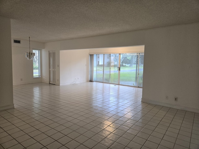 spare room with a chandelier, visible vents, a textured ceiling, and light tile patterned floors