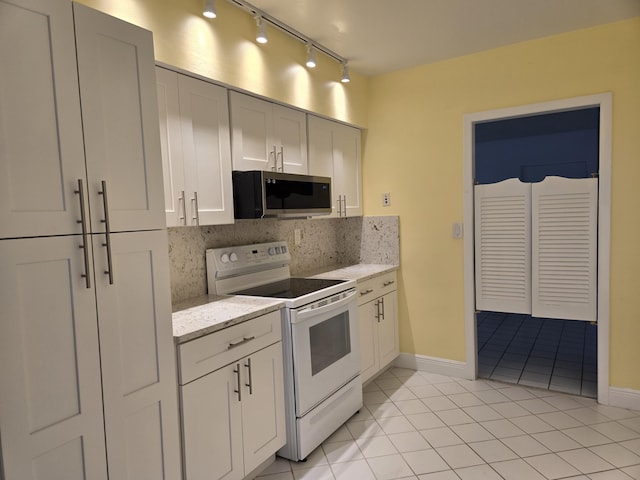 kitchen with tasteful backsplash, stainless steel microwave, electric range, white cabinetry, and light stone countertops