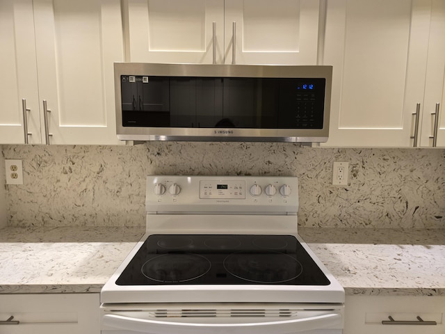 kitchen featuring white range with electric stovetop, stainless steel microwave, white cabinets, and backsplash