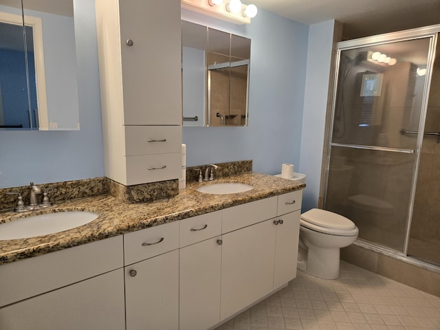 full bath featuring double vanity, a stall shower, a sink, and toilet