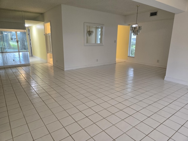 unfurnished room with baseboards, visible vents, an inviting chandelier, and light tile patterned floors