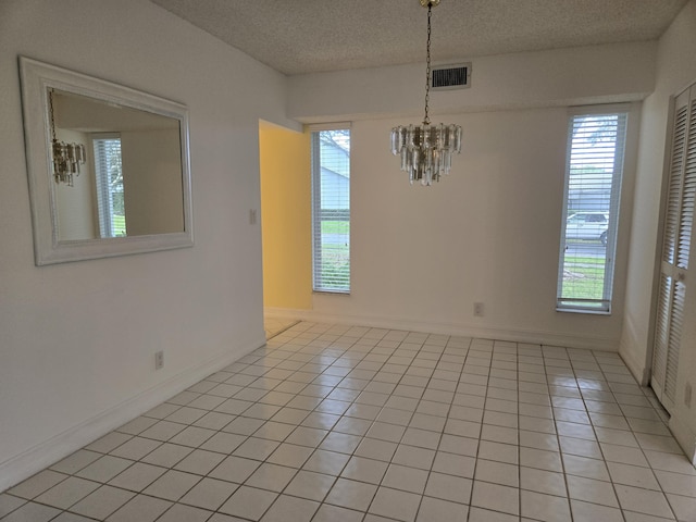 unfurnished dining area featuring a textured ceiling, a chandelier, light tile patterned flooring, visible vents, and a healthy amount of sunlight