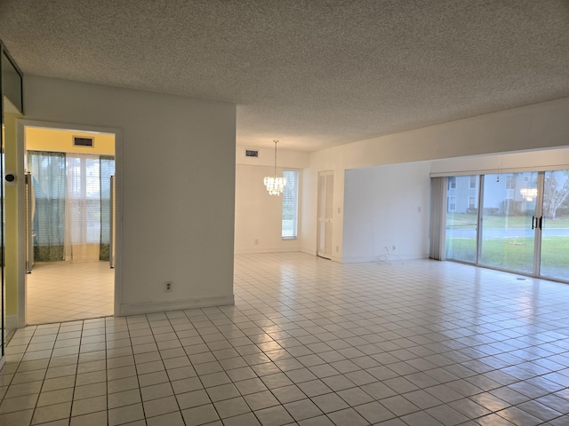 spare room with a wealth of natural light, visible vents, and a notable chandelier