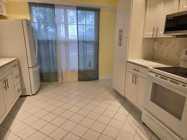 kitchen featuring white appliances, light tile patterned flooring, backsplash, and white cabinetry