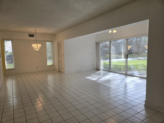 spare room featuring a chandelier, visible vents, a textured ceiling, and light tile patterned floors