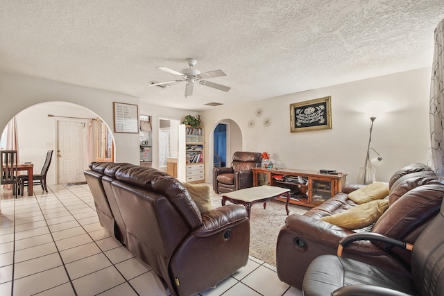 tiled living room with a textured ceiling and ceiling fan