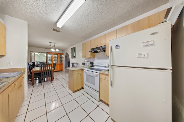 kitchen with kitchen peninsula, light brown cabinetry, light tile patterned floors, an inviting chandelier, and white appliances