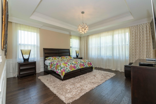 bedroom featuring a raised ceiling, crown molding, dark wood-type flooring, and an inviting chandelier