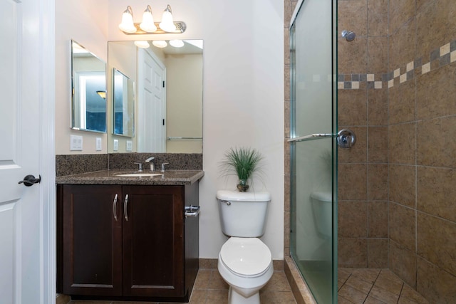 bathroom featuring tile patterned flooring, vanity, toilet, and a shower with door