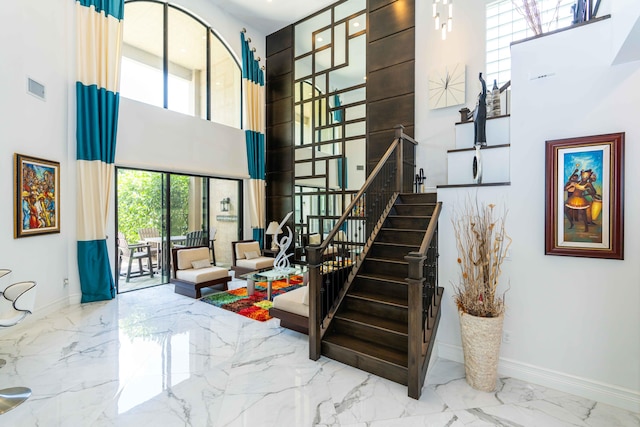 staircase featuring a towering ceiling and a healthy amount of sunlight