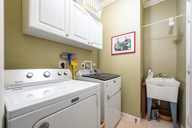 clothes washing area with cabinets, light tile patterned floors, washer and dryer, and ornamental molding