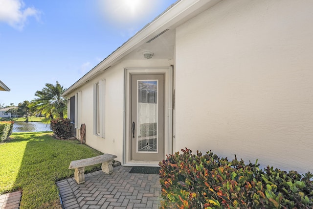 doorway to property featuring a lawn and a water view