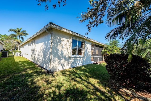 view of side of property featuring a sunroom, cooling unit, and a yard