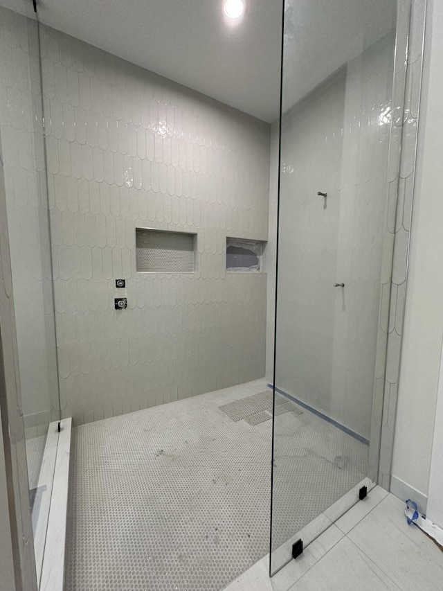 bathroom with a tile shower and tile patterned flooring