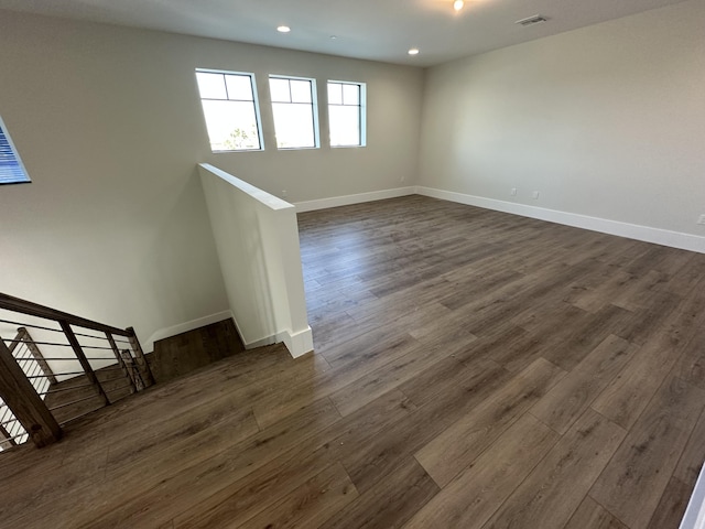 spare room featuring baseboards, visible vents, dark wood-style flooring, stairs, and recessed lighting