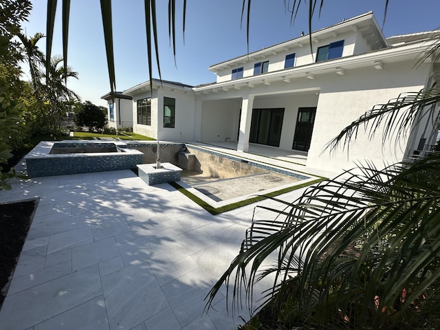 rear view of property featuring a patio area, an empty pool, and stucco siding