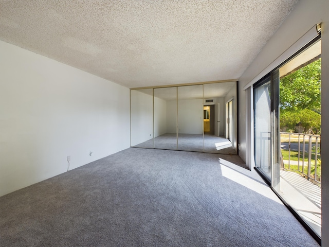 spare room featuring a wealth of natural light, a textured ceiling, and carpet