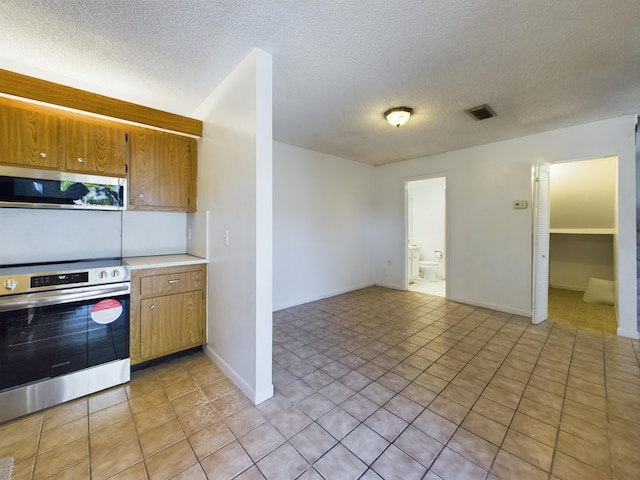 kitchen with appliances with stainless steel finishes, a textured ceiling, and light tile patterned flooring