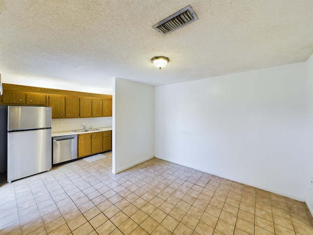 kitchen with stainless steel appliances, light tile patterned flooring, a textured ceiling, and sink