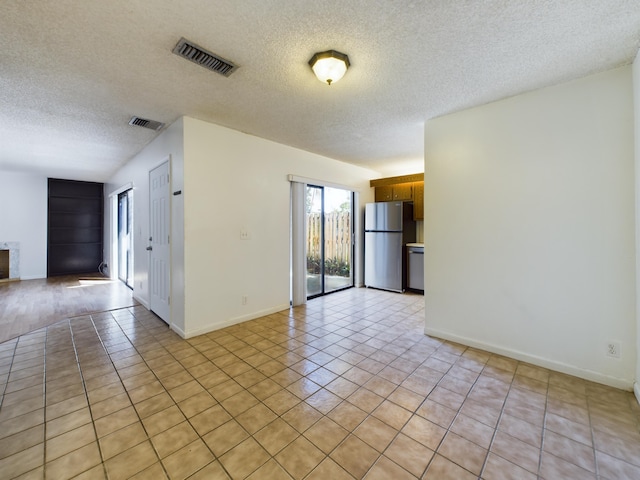 spare room with a textured ceiling and light tile patterned flooring