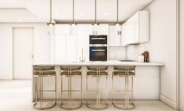 kitchen with white cabinets, stainless steel double oven, a kitchen breakfast bar, and hanging light fixtures