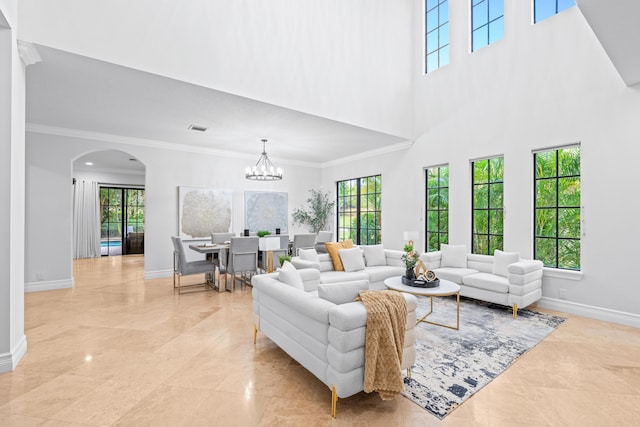 living room featuring a high ceiling, a chandelier, and ornamental molding